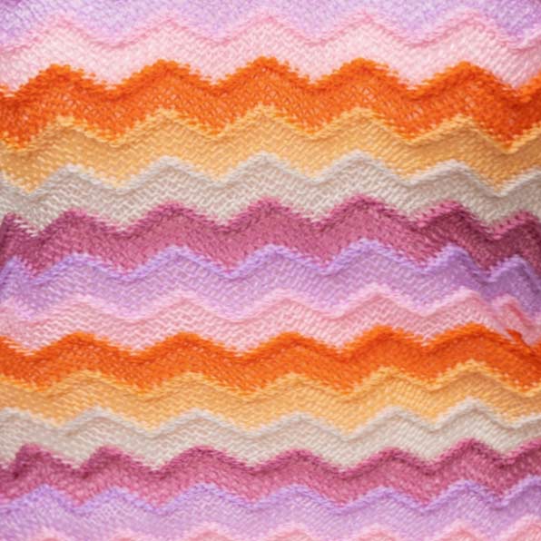 Close-up of colorful yarn with a wave pattern in shades of orange, pink, and purple