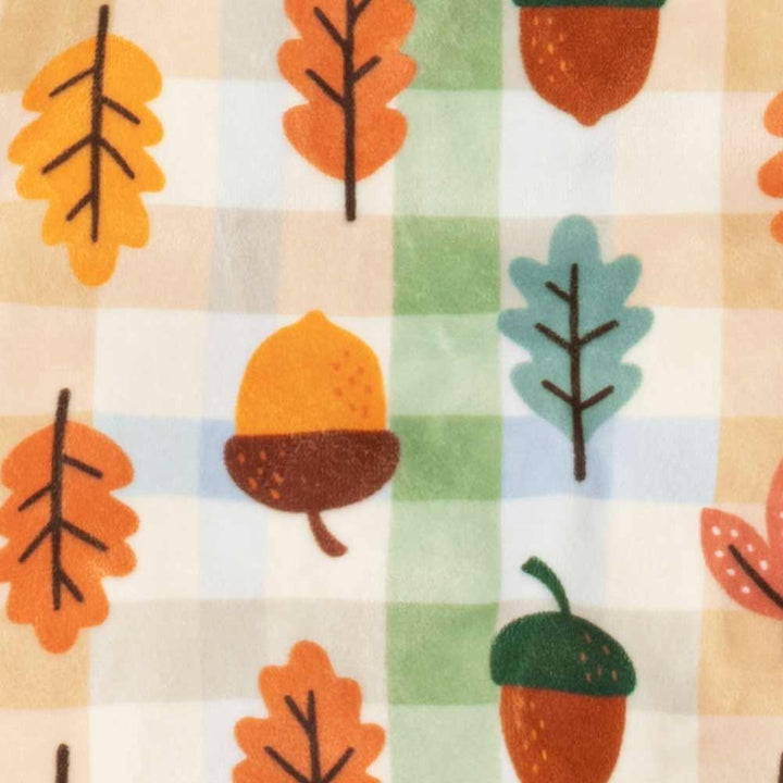 Close-up of a fabric pattern featuring a soft beige and white gingham background with a repeating print of autumn leaves and acorns