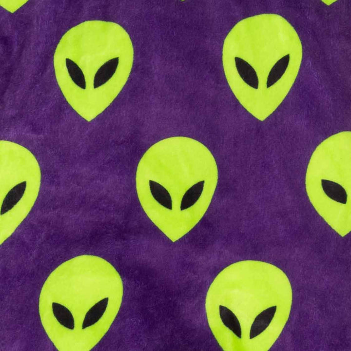 Close-up of a purple fabric with a repeating pattern of bright lime green alien heads with black eyes