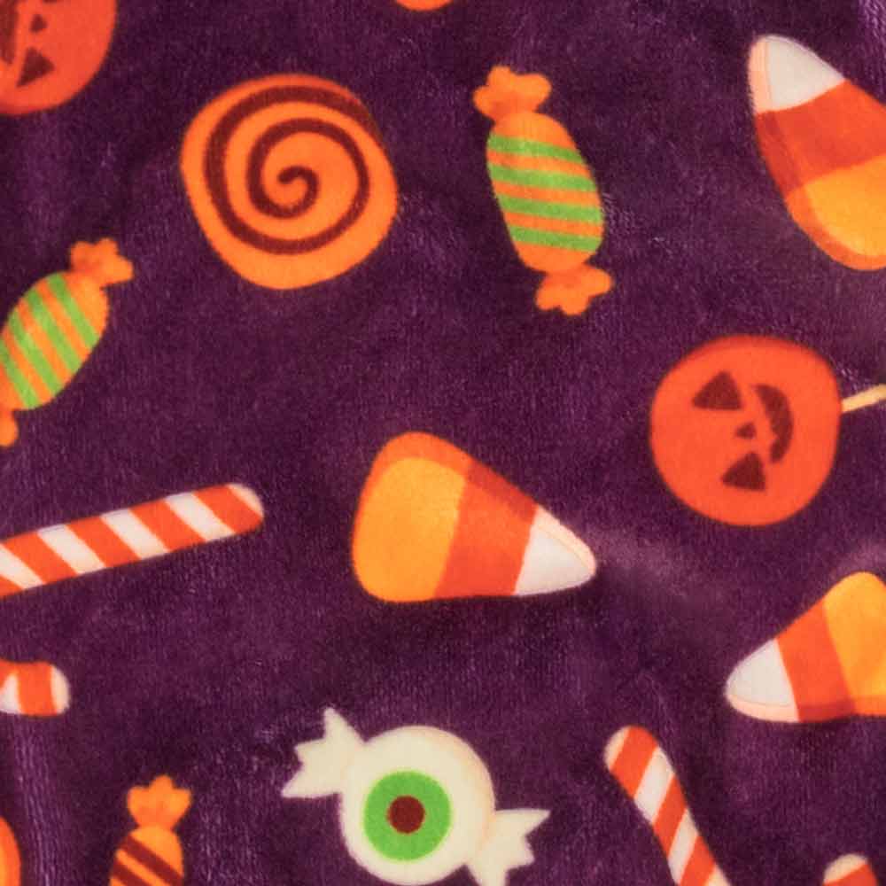 Soft purple Halloween dog pajama fabric with a playful pattern of candy corn, spiral lollipops, and eyeball treats.