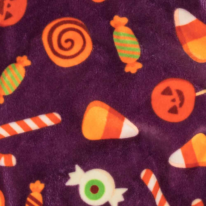 Soft purple Halloween dog pajama fabric with a playful pattern of candy corn, spiral lollipops, and eyeball treats.