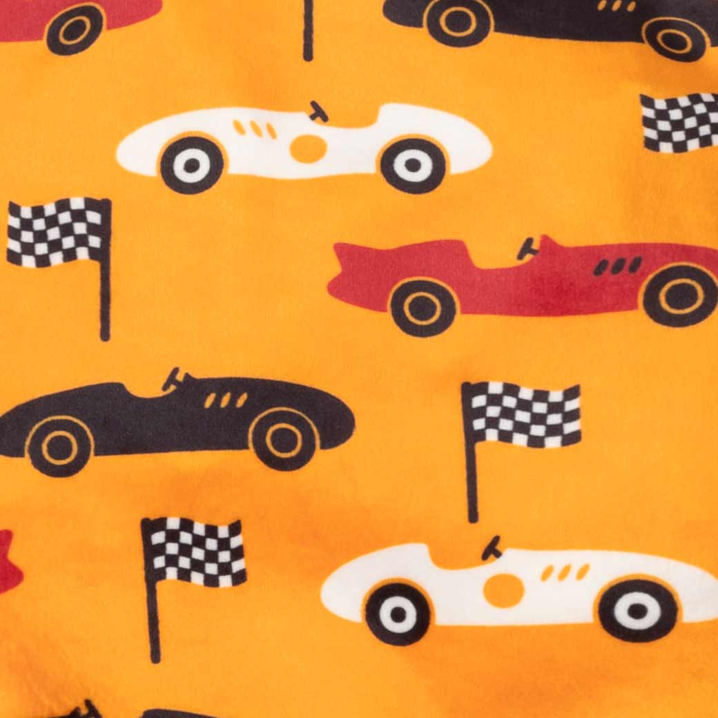 Close-up of a fabric pattern featuring retro race cars in red, black, and white on a bright orange background, interspersed with black-and-white checkered flags