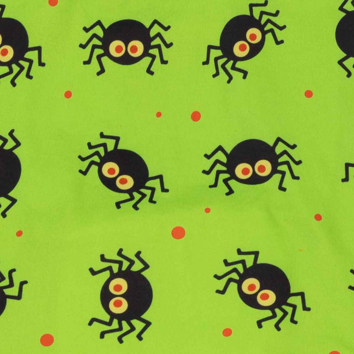 Bright lime green fabric featuring a repeating pattern of black cartoon spiders with yellow and orange eyes, accented by small orange polka dots