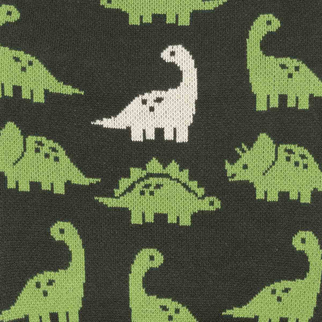 Close-up of a knitted fabric with a repeating dinosaur pattern on a dark charcoal background