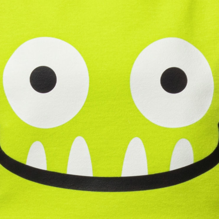 Close-up of a bright lime green fabric with a cartoon monster face graphic featuring large white eyes, black pupils, white teeth, and a black curved mouth