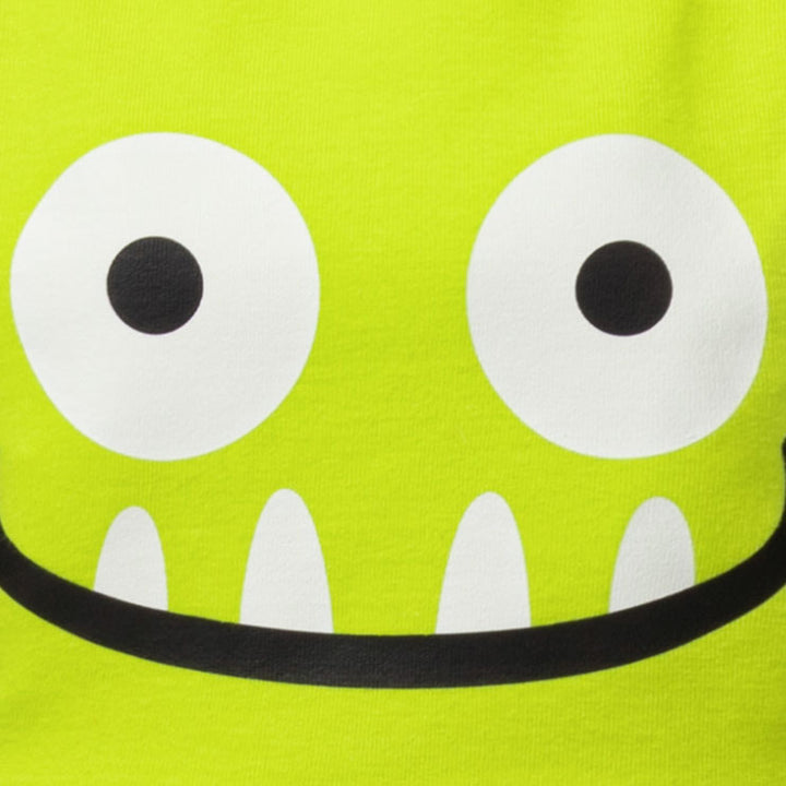 Close-up of a bright lime green fabric with a cartoon monster face graphic featuring large white eyes, black pupils, white teeth, and a black curved mouth