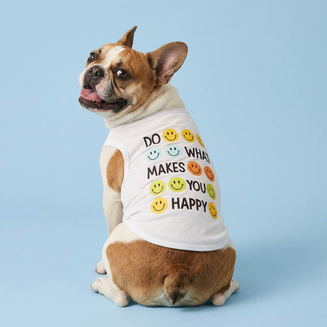 Back view of dog wearing a white sleeveless dog t-shirt with smiley face text on a blue background