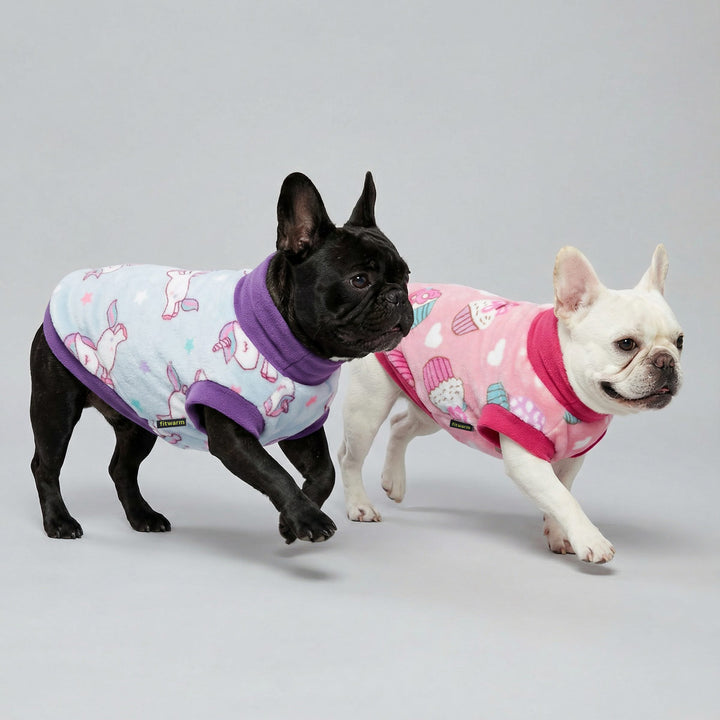 Two French bulldogs walking side by side wearing pastel fleece dog sweaters styles with playful prints