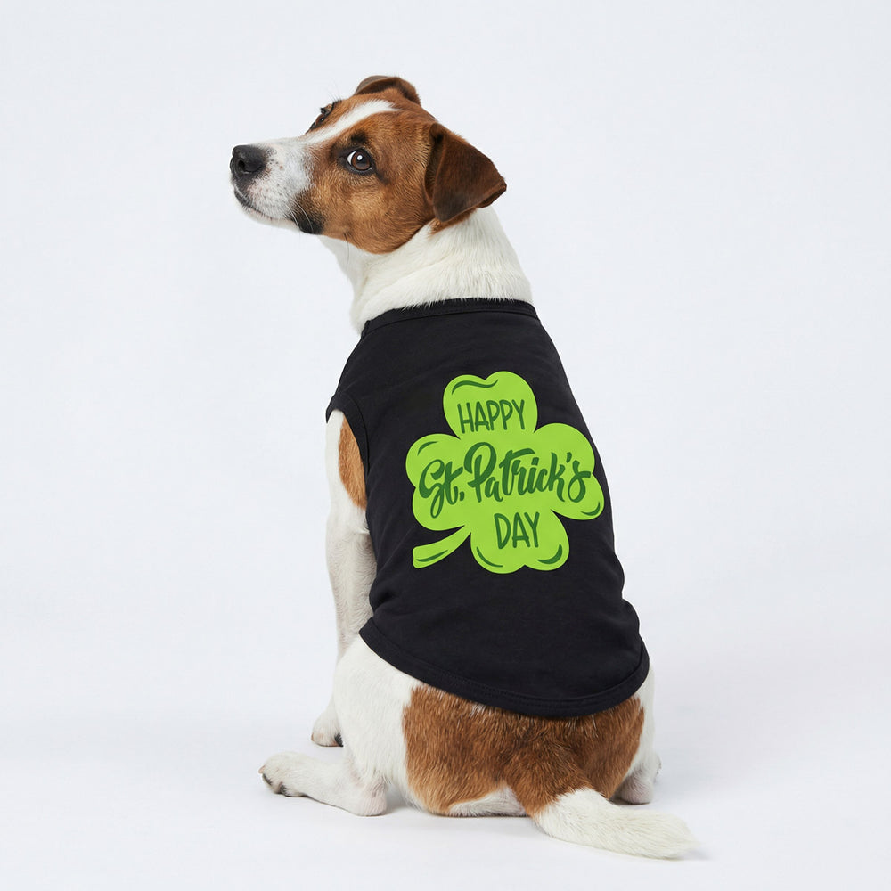 Dog wearing a black dog shirt with a green shamrock and 'Happy St. Patrick's Day' lettering on a white background