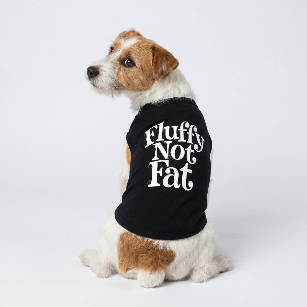 Dog looks back in a black shirt for dogs with 'Fluffy Not Fat' lettering on a white background