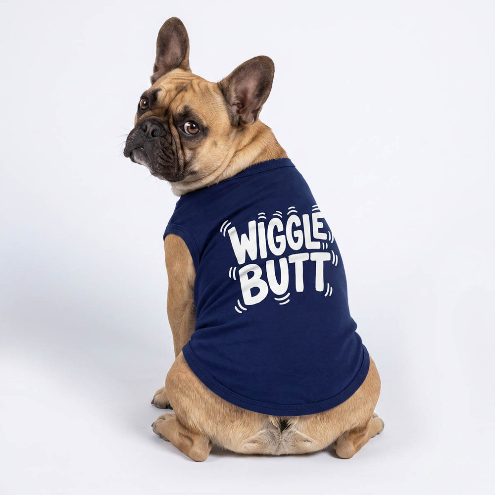 Back view of French Bulldog wearing a navy blue sleeveless shirt for dogs with 'WIGGLE BUTT' printed in white, photographed against a seamless white studio background
