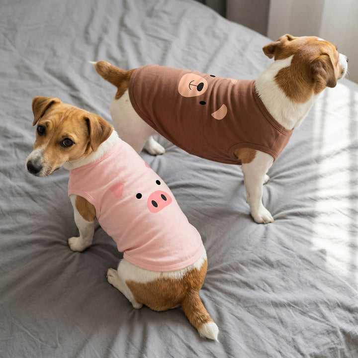 Two dogs wearing animal-themed shirt for dogs on a bed